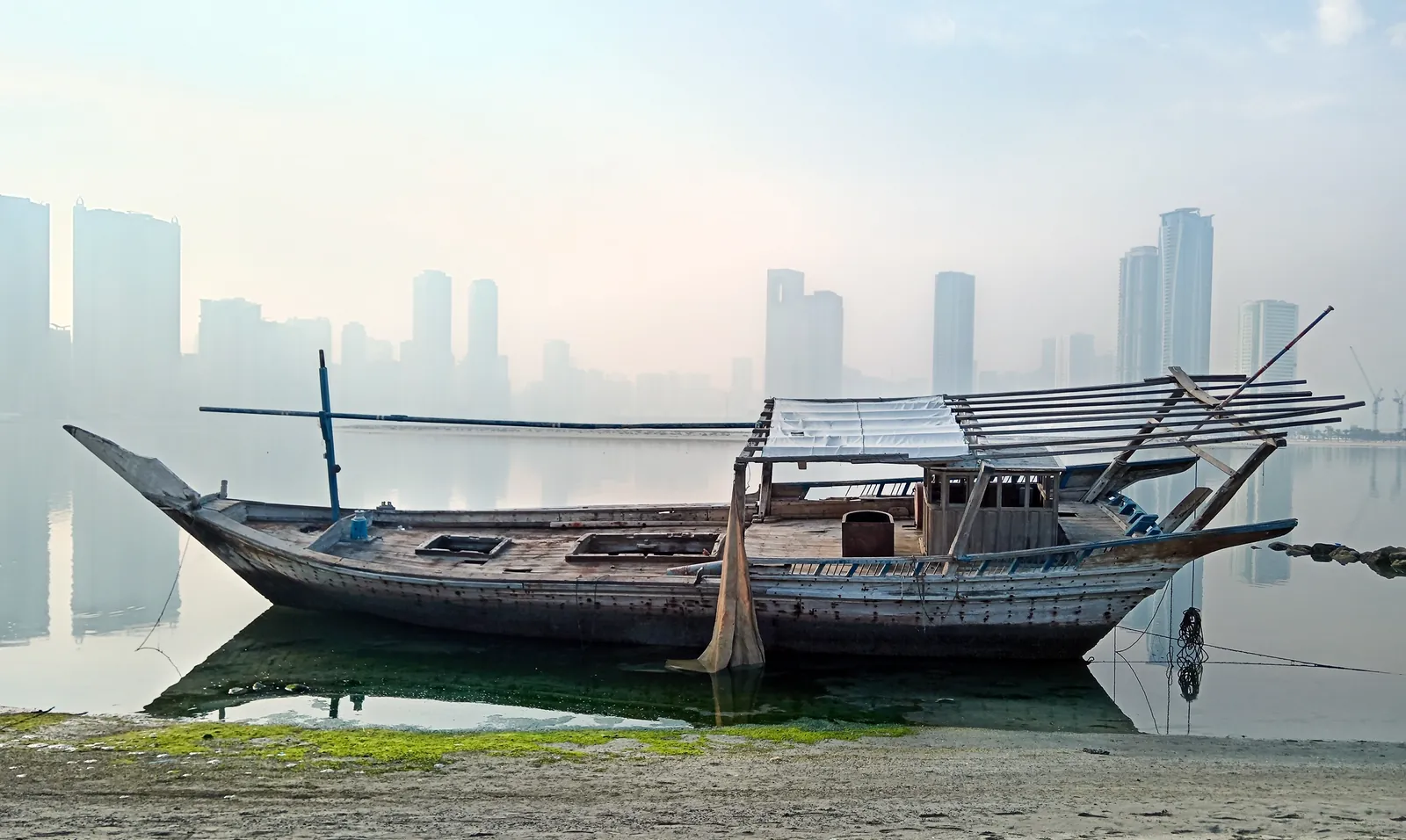 Boutre sur la plage d'Al Khan, tours de Sharjah dans la brume